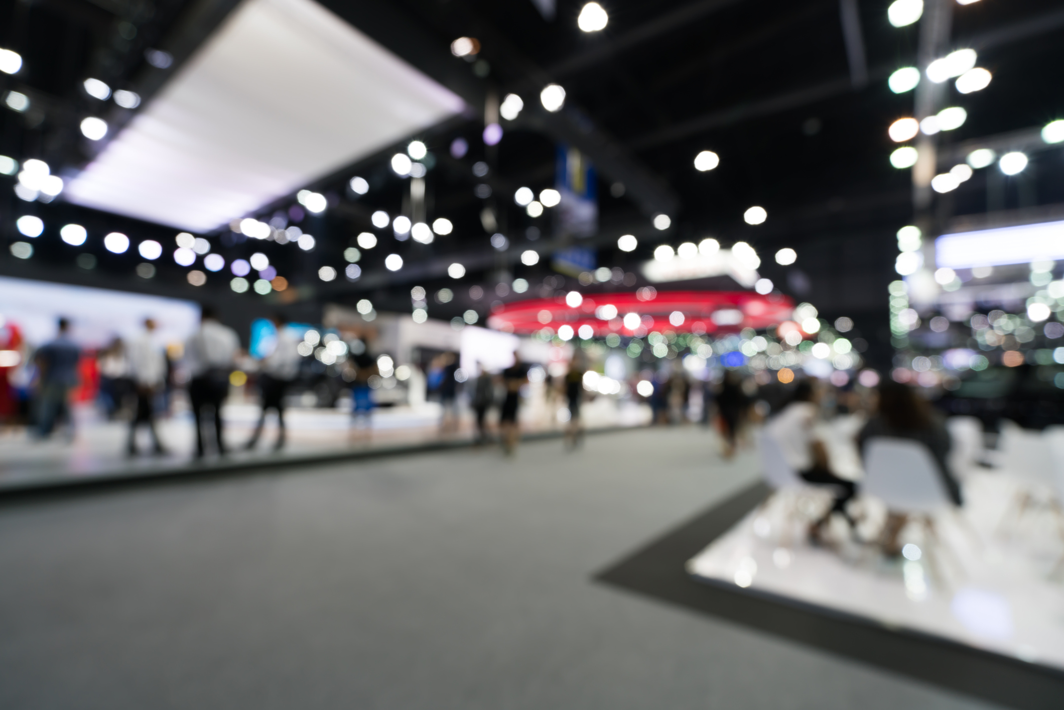 ALT Text: an out of focus image of CES with a crowd of people walking through the convention center  